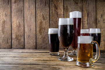 Different sorts of craft beer on wooden bar background. Set of various beer glasses and mugs. Beer tasting concept