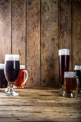 Different sorts of craft beer on wooden bar background. Set of various beer glasses and mugs. Beer tasting concept