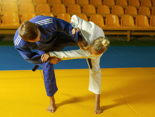 Naklejka premium Martial arts. Sparing Portners. Sport man and woman in white and blue kimono train judo throws and captures in the sports hall