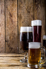 Different sorts of craft beer on wooden bar background. Set of various beer glasses and mugs. Beer tasting concept