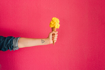 Pineapple Ice cream in the cone on pink background. Handheld. Blurred background.