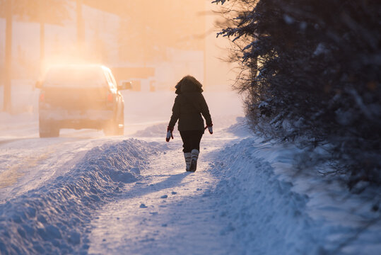 A woman dressed for extreme cold walks through Old Town at sunset in Yellowknife, Northwest Territories, Canada.