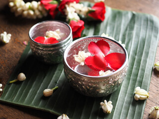 Thai traditional silver bowl of blessing water with rose and jasmine on banana leaf
