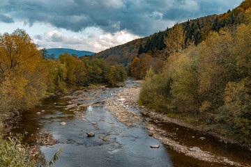 autumn mountain forest dramatic landscape October time scenic view with rocky river stream moody...
