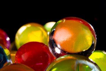 multi-colored silicone gel balls in a glass on a black background