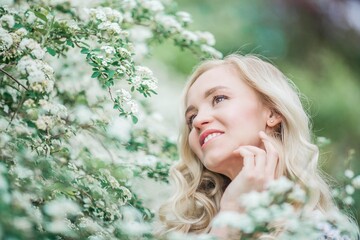 Portrait of a beautiful young blonde in white blossoms. Spring portrait of a young woman.