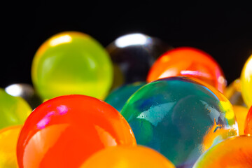 multi-colored silicone gel balls in a glass on a black background