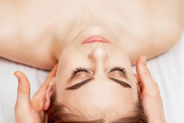 Obraz na płótnie Canvas Top view of beautiful young woman having head massage in spa salon.