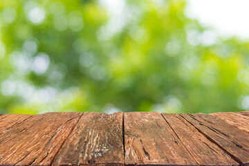 Empty old wooden table in front of blurred  bokeh of natural sunlight and tree in garden background. Can be used for display or montage for show your products.
