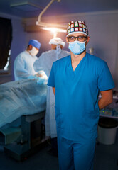 Portrait of young surgical doctor in scrubs standing in operating theatre. Portrait of male doctor in modern medical room.