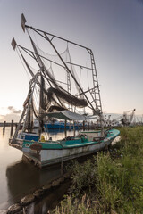 Well worn shrimping boat docked on a shore in the bayou of southern Louisiana