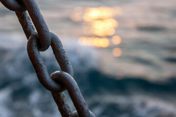 Chain and the sea. Chain close-up on the background of the sea at sunset. Sea waves in the evening out of focus.