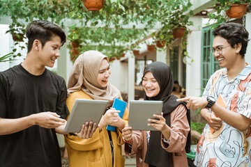 group of asian students chatting together and planning work on a digital tablet