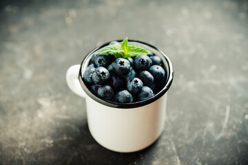 Freshly harvested blueberries in metal cup. Selective focus. Shallow depth of field.
