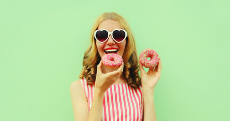 Portrait of cheerful young woman eating donut on a green background, cute caucasian female model with curly hair