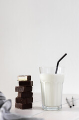 Fresh milk in a glass with black straws, chocolate candies with souffle, tasty healthy drink