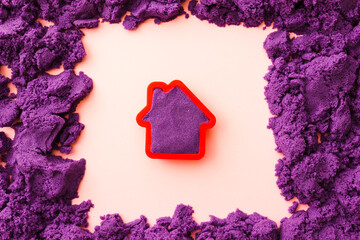 Violet kinetic sand in shape of house in a red frame. Development of fine motor skills. educational...