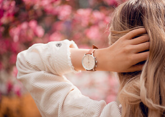 Stylish retro white watch on woman hand in flowers