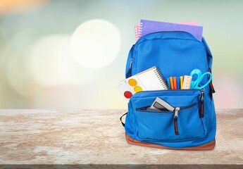 Classic school backpack with colorful school supplies and books on the desk.