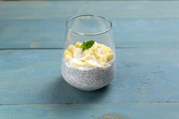 Chia pudding with a sprig of mint in a glass cup on a blue wooden background. Copy space. A healthy...