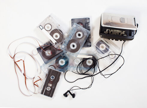 Vintage walkman cassette player with earphones and lots of cassette tape on white background. Old-fashioned background.