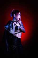 Portrait of a young sexy tattooed cyberpunk woman wearing a studded leather jacket over her shoulder