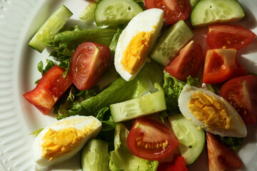 rustic summer salad with fresh cucumbers, tomatoes and eggs on a white plate. the view from the top