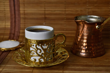 gold cups and Turk for coffee on a light background