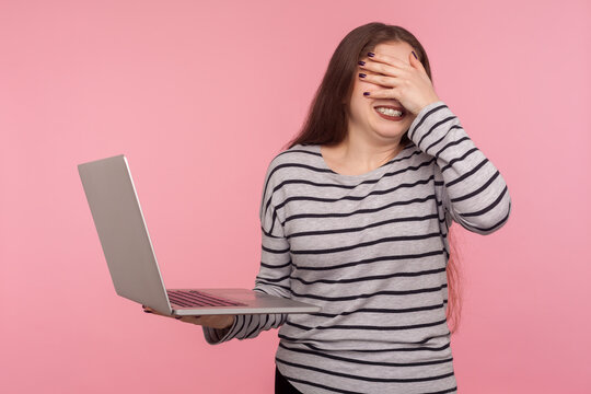 Oops, don't want to look! Portrait of woman covering eyes, feeling frustrated worried about software problems on laptop, failed update, shocked and scared of forbidden content. studio shot isolated