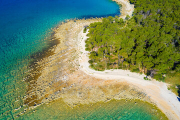 Aerial view of the rocky coast with the pebble beach and pine forest near Pakostane in Dalmacija