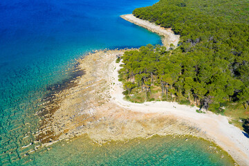 Aerial view of the rocky coast with the pebble beach and pine forest near Pakostane in Dalmacija