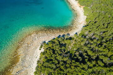 Aerial view of the rocky coast with the pebble beach and pine forest near Pakostane in Dalmacija