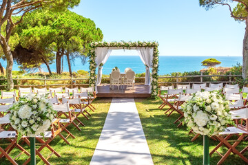 Beautiful wedding ceremony on the ocean. White path lined to an arch decorated with flowers.