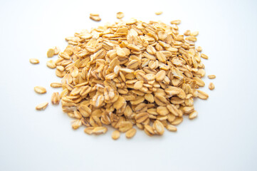A small pile of dry oatmeal on a white background.