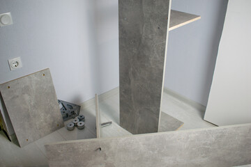 Room with blue plastered walls. Gray wood wardrobe. Components for assembling a new cabinet on the...
