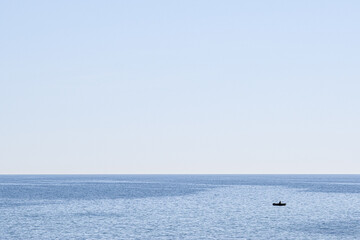 a boat in the sea - very small relative to the big blue ocean