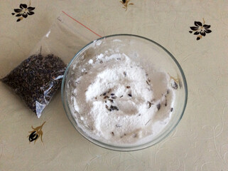 A bag with zip lock of dried lavender. Ingredients and floral decor, salt for bathbomb in glass bowl on table.