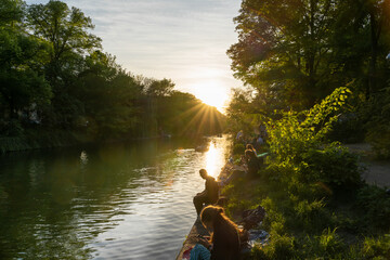 People sitting at riverside of Landwehrkanal in Berlin Kreuzberg while sunset