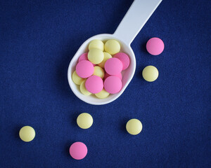 Colored pills on the table. Medical drugs on a blue background. Place for text.