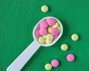 Colored pills on the table. Medical preparations on a green background. Place for text.
