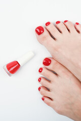 Female legs and red nail polish on a white background.