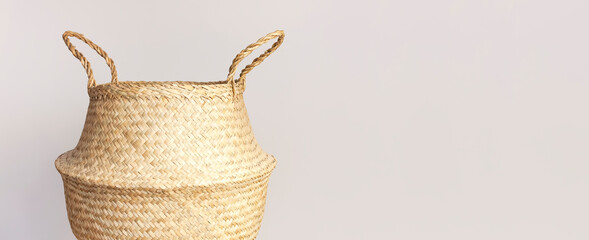 Empty straw wicker basket on a gray background. Fashionable bamboo basket, stylish interior item,...