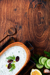 Traditional Greek sauce Tzatziki in olive wooden bowl on old rustic background. Top view.