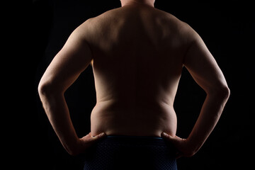 rear view of a man with hands on waist on black background