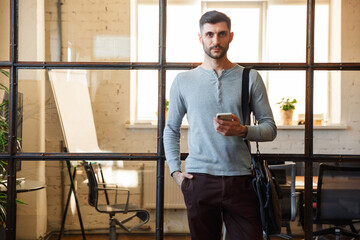 Photo of handsome caucasian man using cellphone while standing