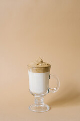 Beautiful dalgon drink coffee with foam in a transparent mug on a beige background