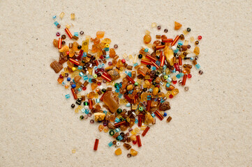 Love, Valentine theme, heart shape, relations, amber and beads on white sand background.