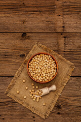 Dry chickpea in ceramic bowl on old wooden boards background. Traditional ingredient for cooking hummus