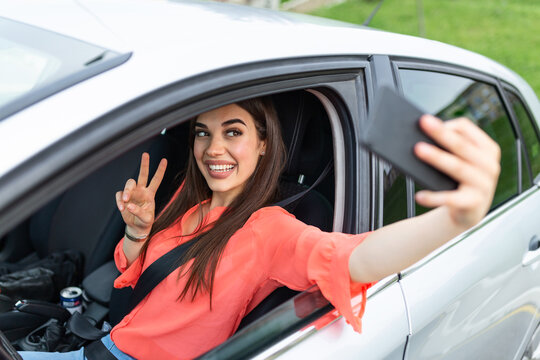 Smiling young woman taking selfie picture with smart phone camera outdoors in car. Holidays and tourism concept - smiling teenage girl taking selfie picture with smartphone camera outdoors in car