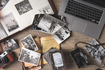 Old family photos and album on wooden background. Vintage pictures, camera, notepad and modern notebook composition. Flat lay.